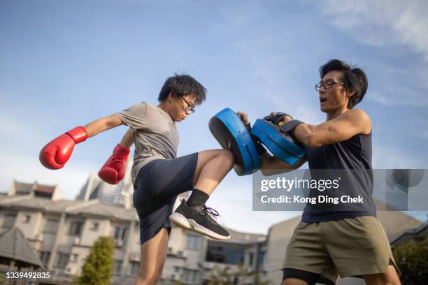 asian chinese father and son training kickboxing at backyard outdoor. - kid boxing stock pictures, royalty-free photos & images