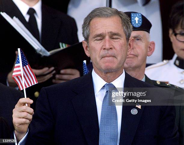 President George W. Bush holds an American flag during a Memorial Service at the Pentagon October 11, 2001 in Arlington, Virginia.