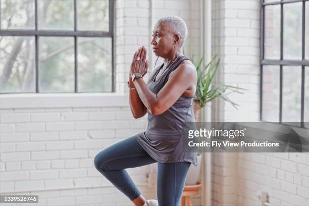 donna anziana attiva che fa yoga a casa - anziani attivi foto e immagini stock