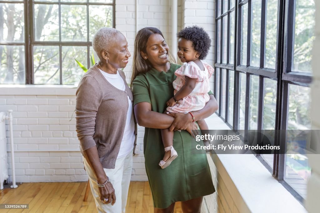 Cute toddler girl spending time with her mom and grandma at home