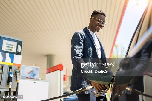ガソリンスタンド彼の車に給油幸せな若いアフリカ系アメリカ人男性。 ガソリンスタンド彼の車に給油幸せな若いアフリカ系アメリカ人男性。