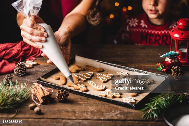 donna glassa pan di zenzero biscotto di natale dal figlio in cucina - baking foto e immagini stock