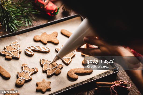 hände einer frau, die weihnachtsplätzchen mit eisbeutel schmücken - backen stock-fotos und bilder
