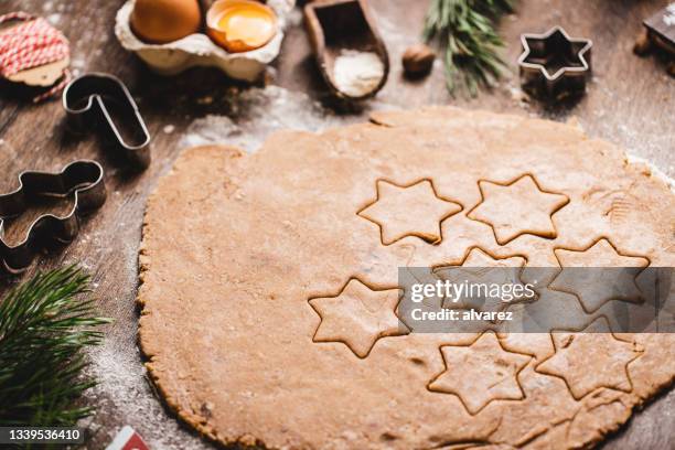 christmas star shapes on flattened cookie dough in kitchen - pastry cutter stockfoto's en -beelden