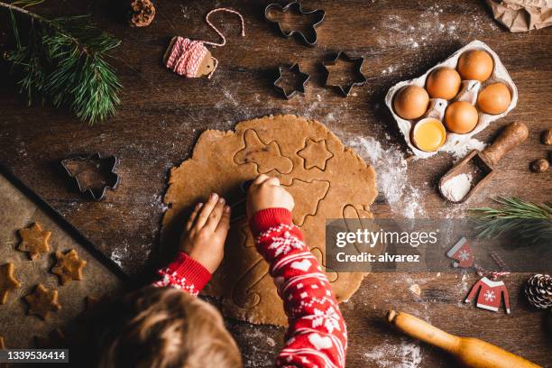 boy cutting dough with christmas cookie cutters on table - baking stockfoto's en -beelden