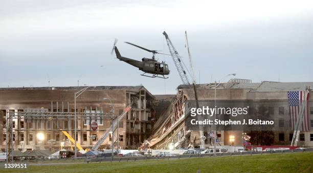 Military helicopter flies in front of the Pentagon September 14, 2001 in Arlington, Virginia at the impact site where a hijacked airliner crashed...