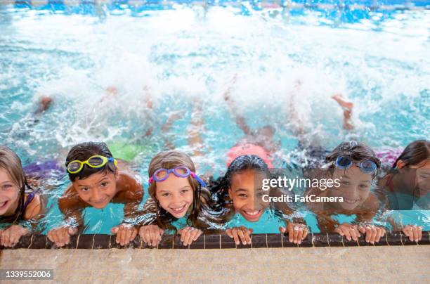 multi ethnic group of children learning to kick in the swimming pool - swimming imagens e fotografias de stock