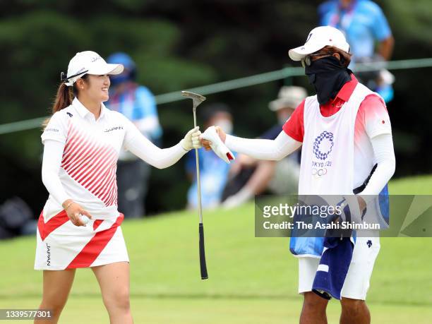 Mone Inami of Team Japan fist bumps with her caddie after the birdie on the 15th green during the final round of the Women's Individual Stroke Play...