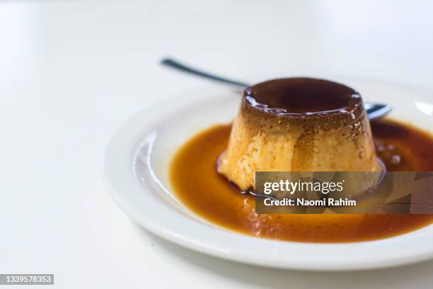 crème caramel dessert, surrounded by caramel sauce on a white plate - caramel sauce photos et images de collection