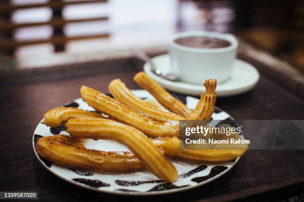 spanish hot chocolate and churros dusted with sugar, in a spanish cafe - churro stockfoto's en -beelden