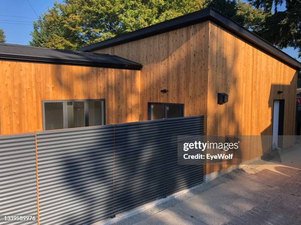 a newly built adu with a black metal corrugated fence along an alley. - metal fence stock pictures, royalty-free photos & images