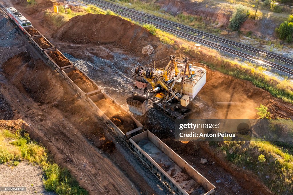Large excavator loads iron ore into train carriages