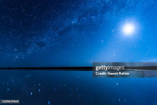 vivid blue night sky, milky way galaxy and full moon shining in a starry sky, reflecting over lake tyrrell, australian landscape - melbourne star stock pictures, royalty-free photos & images