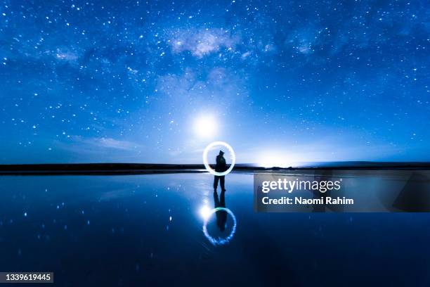 person light painting illuminated circle in sparse lake landscape, milky way galaxy and vivid blue night sky - dramatic night sky stock pictures, royalty-free photos & images