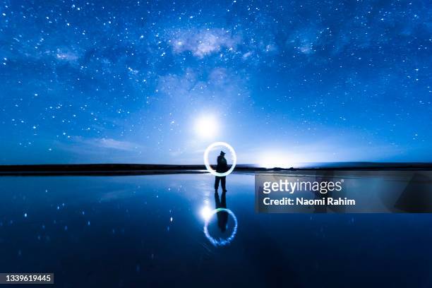 person light painting illuminated circle in sparse lake landscape, milky way galaxy and vivid blue night sky - bar silhouette bildbanksfoton och bilder