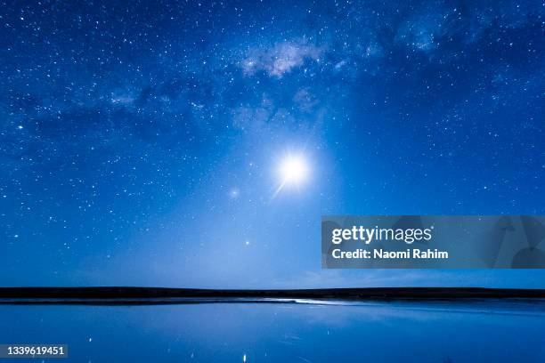 vivid blue night sky with milky way and full moon shining brightly over a lake - melbourne star stock pictures, royalty-free photos & images