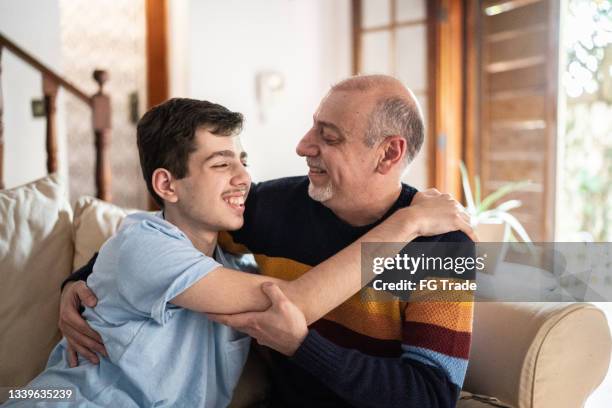 father and son hugging each other at home - epilepsy stock pictures, royalty-free photos & images