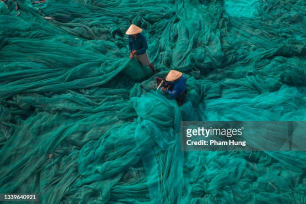 two men is fixing fishing net - vietnam stockfoto's en -beelden