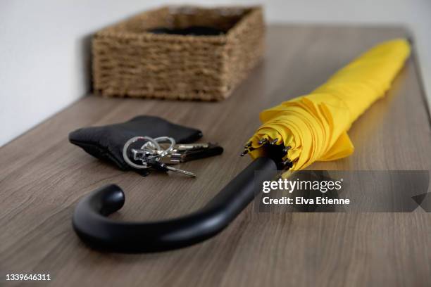 yellow umbrella, purse and keys on a side table in a domestic hallway. - car keys table stock-fotos und bilder