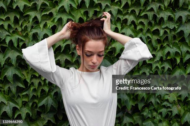 woman with freckles fixing hair - ginger bush stock pictures, royalty-free photos & images