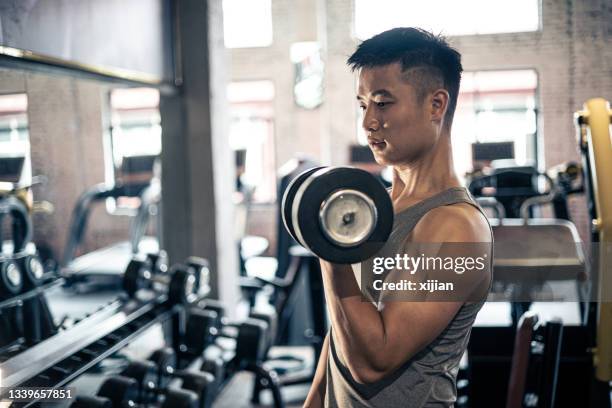 man doing exercise with dumbbell in gym - weightlifting room stock pictures, royalty-free photos & images