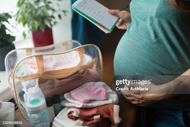 pregnant woman preparing bag for the hospital for childbirth - bag stockfoto's en -beelden