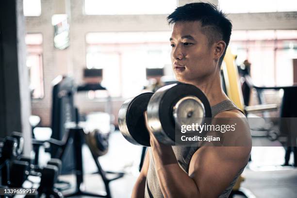 man doing exercise with dumbbell in gym - weightlifting room stock pictures, royalty-free photos & images