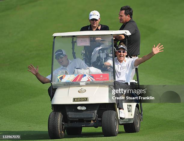 Justin Rose and Ian Poulter of England wave from their buggie during practice for the Omega Mission Hills World Cup at the Mission Hills' Blackstone...