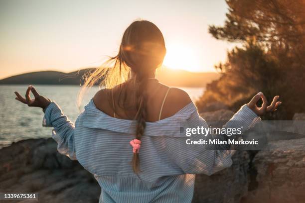 une jeune femme au bord de la mer fait du yoga et médite - woman fresh air photos et images de collection