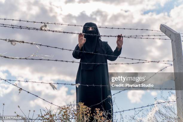 refugee woman  standing behind a fence - afghan bildbanksfoton och bilder