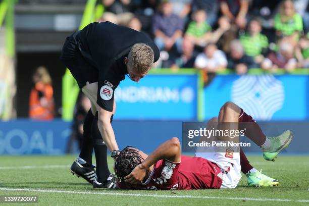 Referee Scott Oldham looks at Shaun McWilliams of Northampton Town as he lays on the ground after a clash during the Sky Bet League Two match between...