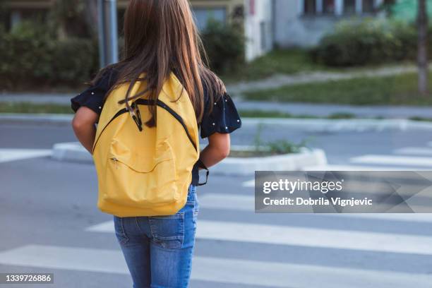 school girl with yellow school bag on a crosswalk - skolväska bildbanksfoton och bilder