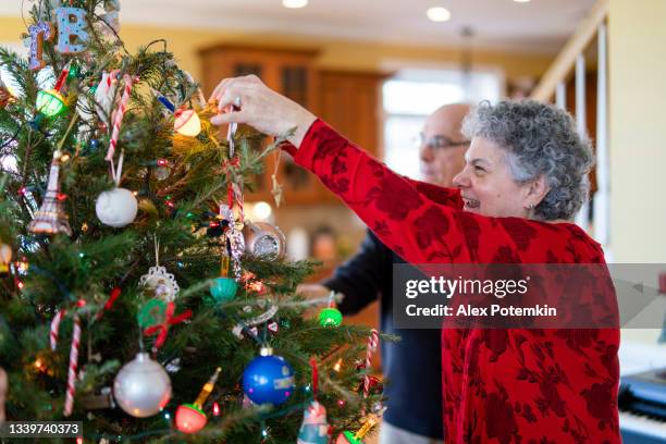 the senior couple, a 73-years-old man and 65-years-old woman, decorating christmas tree together. - 60 69 years bildbanksfoton och bilder