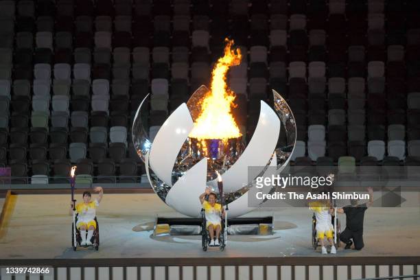 Yui Kamiji , Shunsuke Uchida , Karin Morisaki of Team Japan light the Paralympic flame during the opening ceremony of the Tokyo 2020 Paralympic Games...