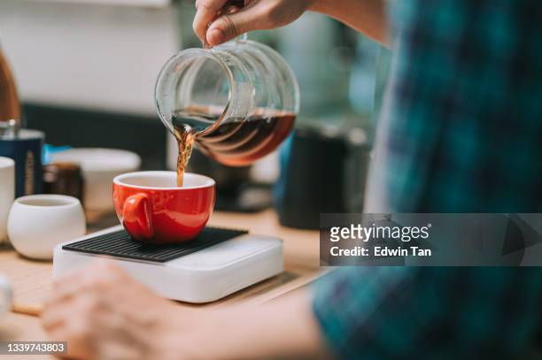 nahaufnahme asiatischer chinesischer männlicher barista hand gießen brühkaffee von kaffeekanne zu keramik kaffeetasse auf gewichtsskala - filterkaffee stock-fotos und bilder