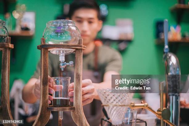 asiatischer chinesischer männlicher barista bereitet cold brew eistropfkaffee im café coffee shop zu - filterkaffee stock-fotos und bilder