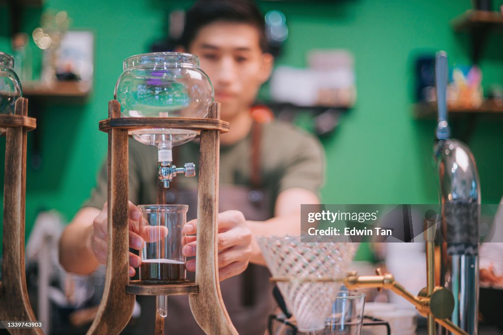 Barista asiático chino prepara café frío con hielo de hielo en la cafetería