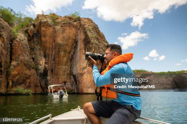 photographer sitting boat takes a picture river - eco tourism stock pictures, royalty-free photos & images