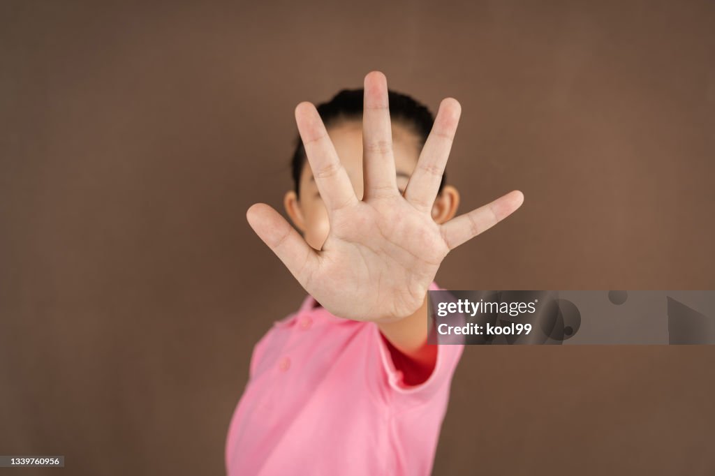 Little Girl Making Stop Gesture on Brown Backgroun