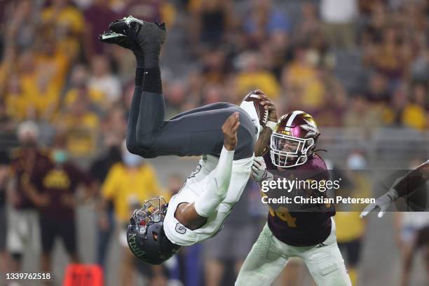 Quarterback Doug Brumfield of the UNLV Rebels flips into the end zone to score on a four-yard rushing touchdown ahead of linebacker Kyle Soelle of...