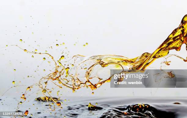 golden oil drops, splashing water - lubricación fotografías e imágenes de stock
