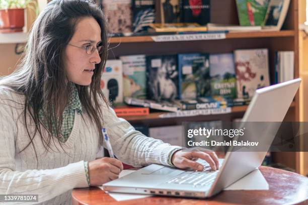 female student studying with laptop in campus library. - openbare bibliotheek stockfoto's en -beelden