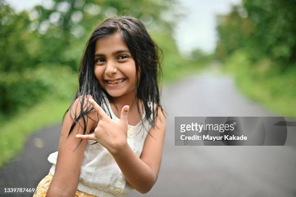 portrait of a cute girl standing amidst road lined up with trees - enjoy monsoon stock-fotos und bilder