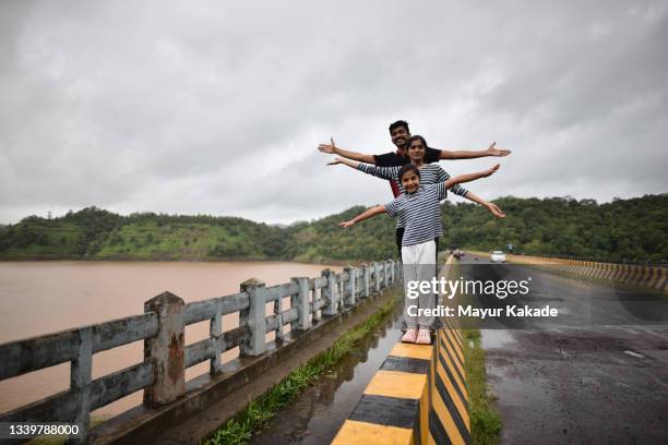 family with arms stretched standing on a  bridge surrounded by a serene lake - monsoon stock pictures, royalty-free photos & images