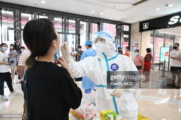 Medical worker collects a throat swab from a staff member for nucleic acid testing at Wanda Plaza on September 11, 2021 in Putian, Fujian Province of...