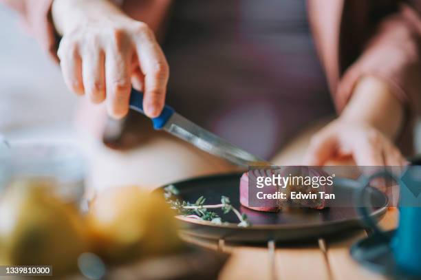 asian chinese woman cutting snow skin mooncake enjoying her afternoon tea with chinese traditional festival dessert at living room - hand pastry stock pictures, royalty-free photos & images