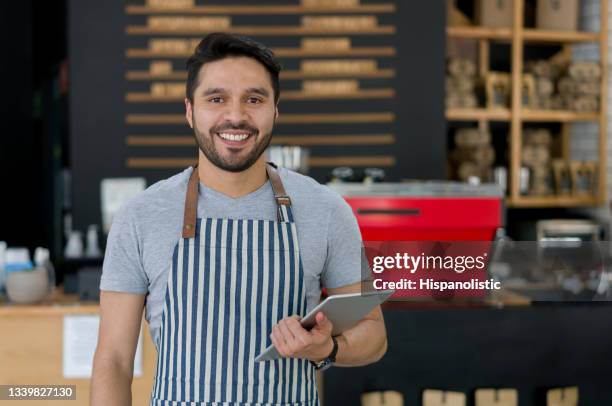 happy waiter working at a cafe and using tablet computer - apron stock pictures, royalty-free photos & images