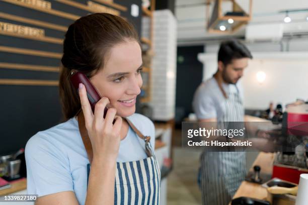 waitress taking a delivery order on the phone at a coffee shop - restaurant manager phone stock pictures, royalty-free photos & images