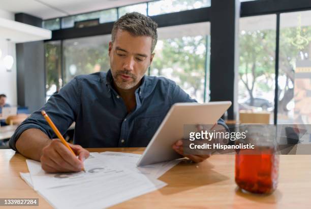 man working at a cafe while drinking a cup of coffee - business plan stock pictures, royalty-free photos & images