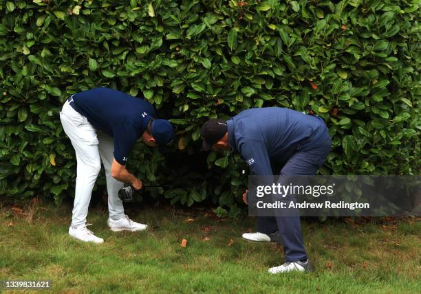 Matthew Fitzpatrick of England looks for his ball in a hedge on the 17th hole with the help from European Tour referee Gary Butler during Day Four of...